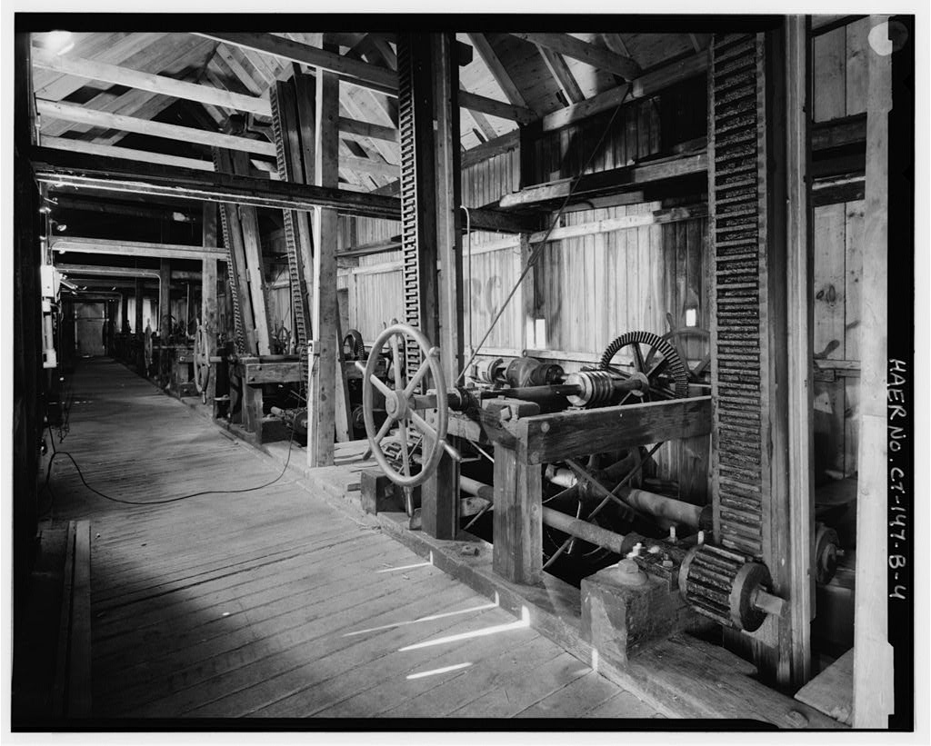 View northwest, interior of gatehouse showing row of gate operating mechanisms; height of stems indicates foreground…