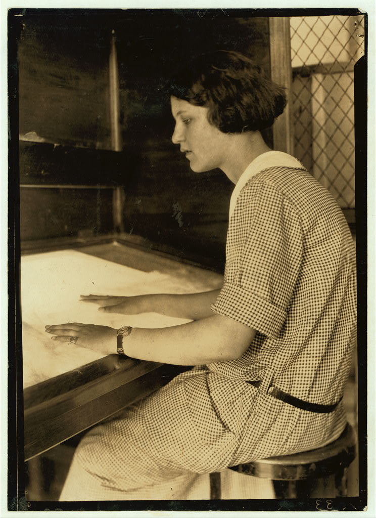 Worker seated at a textile inspection table