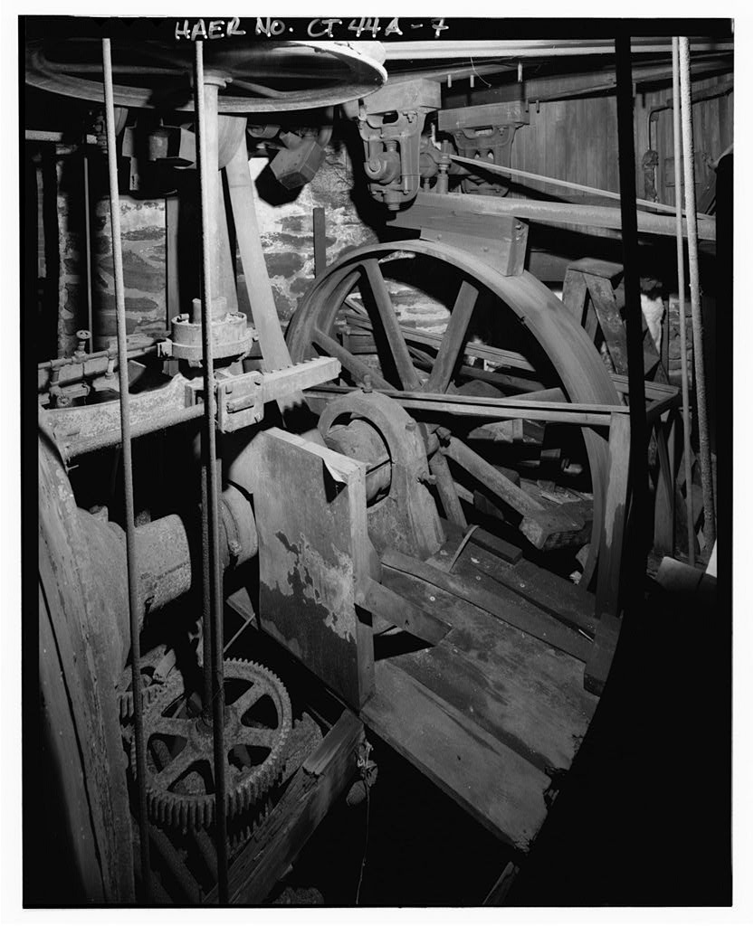 Detail view north of turbine output shaft, flywheel (right center), vertical shaft to governor with rack-and-pinion…