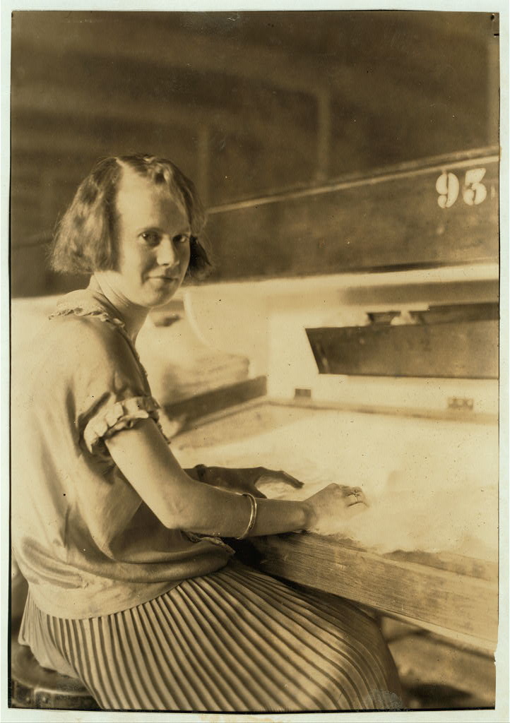 Worker at a lighted textile inspection table